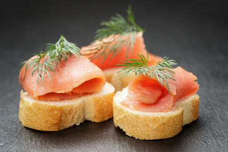baguette slices with curred salmon and dill on slate backgroundの写真素材