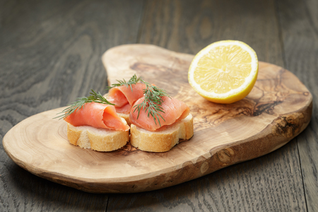 baguette slices with curred salmon and dill on wood tableの写真素材