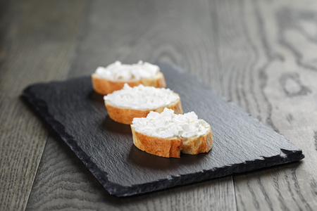 crunchy baguette slices with cream cheese on slate boardの写真素材