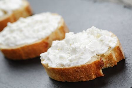 crunchy baguette slices with cream cheese on slate boardの写真素材