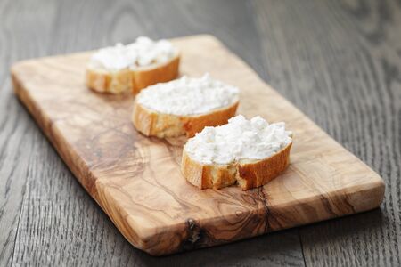crunchy baguette slices with cream cheese on olive boardの写真素材