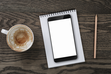 top view of table with empty coffee cup, smartphone and notepad with pencilの写真素材