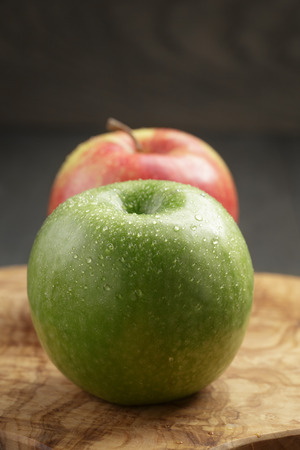 two ripe apples on olive cutting boardの写真素材