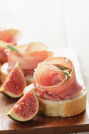 canapes with jamon and figs on wooden boardの写真素材