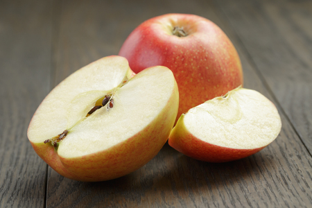 seasonal red apples sliced on wooden tableの写真素材