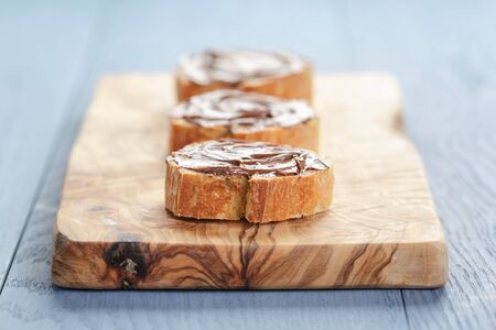 baguette slices with chocolate hazelnut spread on olive board