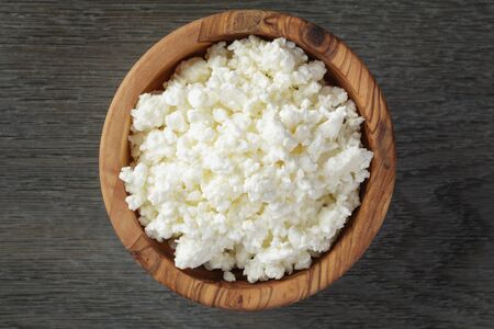 fresh cottage cheese in a wood bowl on a wooden tableの写真素材
