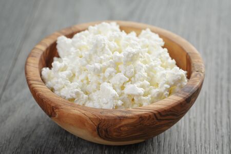 fresh cottage cheese in a wood bowl on a wooden tableの写真素材