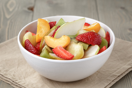 fresh mix fruit salad with strawberry, kiwi and peach, on tableの写真素材