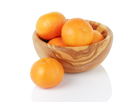 ripe tangerines in wood bowl, isolated on whiteの写真素材