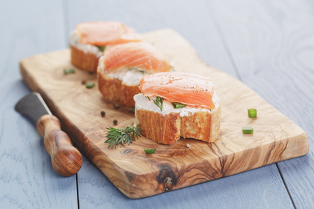 small sandwiches with soft cheese and salmon on wood tableの写真素材
