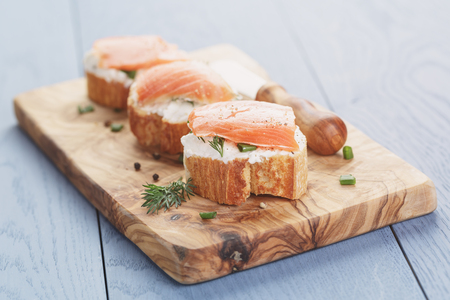 small sandwiches with soft cheese and salmon on wood tableの写真素材