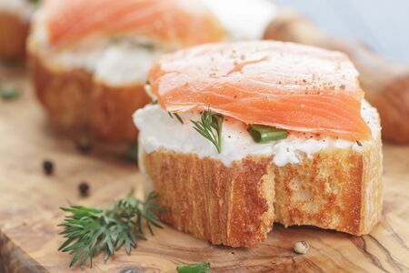 small sandwiches with soft cheese and salmon on wood tableの写真素材