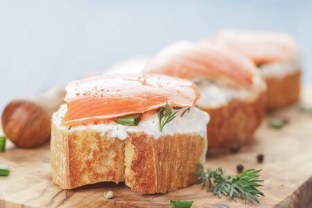 small sandwiches with soft cheese and salmon on wood tableの写真素材