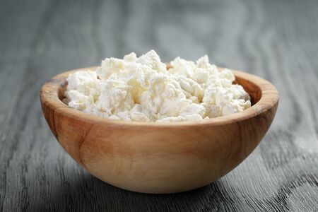 fresh ricotta in olive wood bowl on old tableの写真素材
