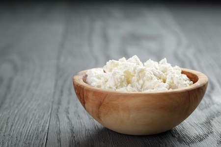 fresh ricotta in olive wood bowl on old tableの写真素材