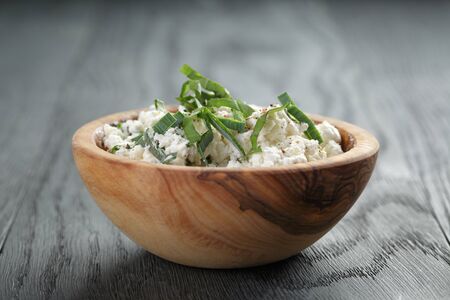 fresh ricotta with herbs in olive wood bowl on old tableの写真素材