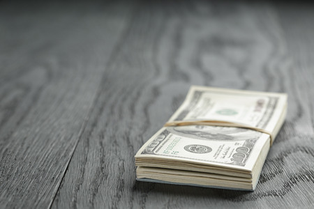 bunch of hundred dollar notes tied with rubberband on wood tableの写真素材