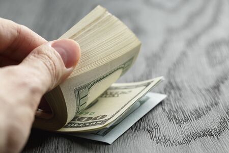 man hands counting dollar notes on wood tableの写真素材