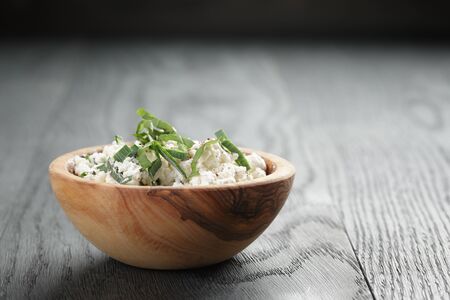 fresh ricotta with herbs in olive wood bowl on old table, shallow focusの写真素材