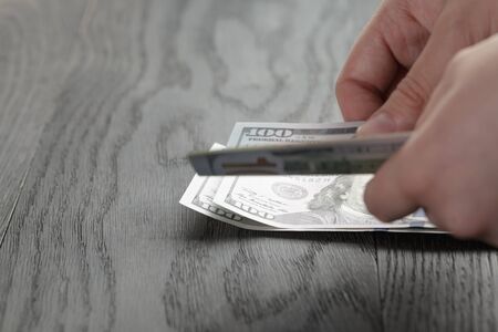 young female hands count dollar bills on wood table, closeupの写真素材