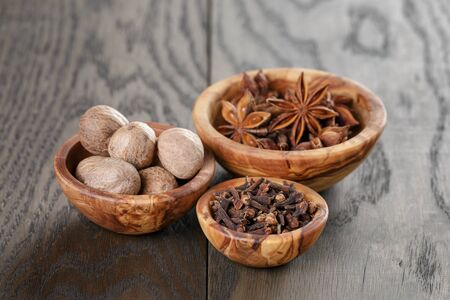 anise stars cloves and nutmeg in olive bowl on oak table, rusticの写真素材