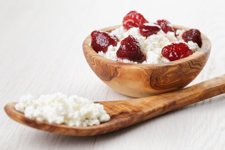 cottage cheese with preserved strawberry in wood bowl on oak table, selective focusの写真素材