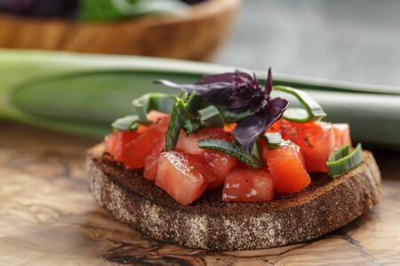 homemade bruschetta with tomatoes, basil and leek on olive boardの写真素材