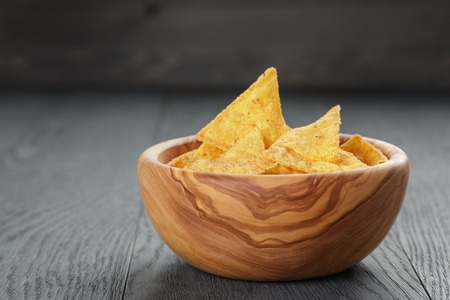 tortilla chips in olive wood bowl on wooden table, selective focusの写真素材