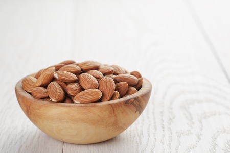 roasted almonds in bowl on white wooden tableの写真素材