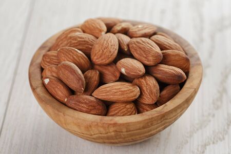 roasted almonds in bowl on white wooden tableの写真素材