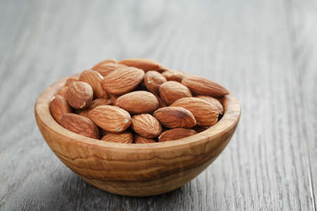 roasted almonds in bowl on gray wooden tableの写真素材
