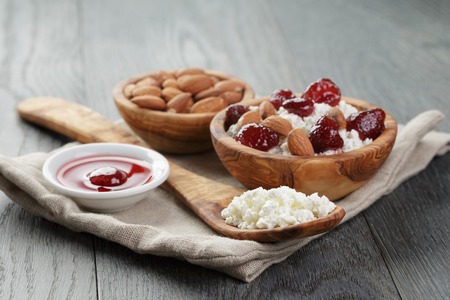 cottage cheese with preserved strawberry in wood bowl on oak tableの写真素材