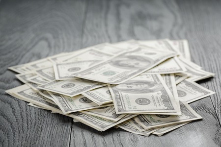 many hundred dollar bills on wooden tableの写真素材