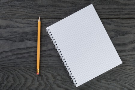 blank notepad with chequered pages on gray wood table and pencilの写真素材
