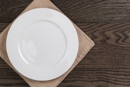 empty white plate on wood table with napkin, top viewの写真素材
