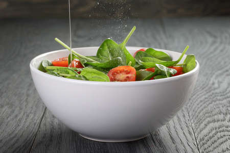 fresh summer organic salad with tomatoes cucumbers and spinach on wooden tableの写真素材