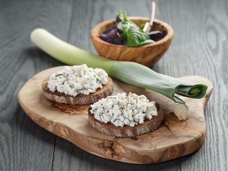 rye sandwiches or bruschetta with ricotta cheese and herbs on wooden tableの写真素材