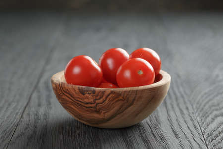 whole cherry tomatoes in olive dowl on old wood tableの写真素材