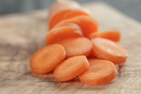 sliced organic carrot on olive wood cutting board, closeup photoの写真素材