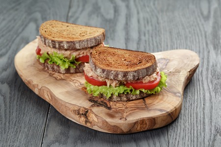 Sandwich with tuna and vegetables on rye bread on wood backgroundの写真素材