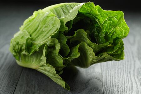 fresh romain green salad on wood table, closeup photoの写真素材