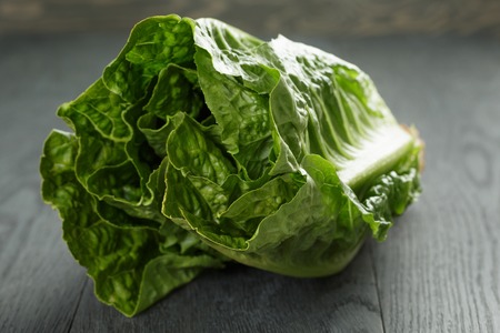 fresh romain green salad on wood table, closeup photoの写真素材