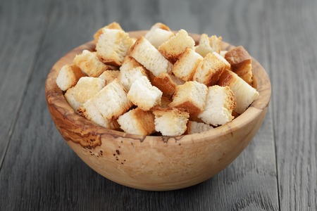 homemade croutons from white bread in wood bowl on oak tableの写真素材