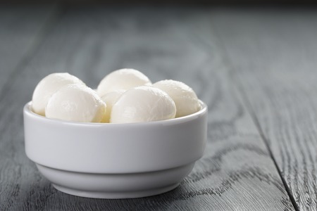 small balls of mozzarella in bowl on wood table
