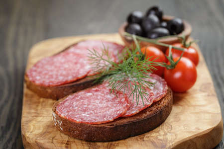 rye sandwich with salami and tomatoes on wood table, vintage tonedの写真素材