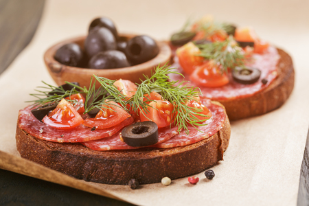 rye sandwich with salami and tomatoes on wood table, vintage tonedの写真素材