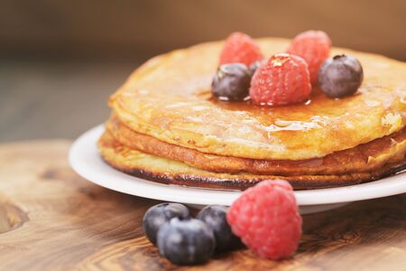 Pancakes with raspberry, blueberry and maple syrup, on oak wooden tableの写真素材