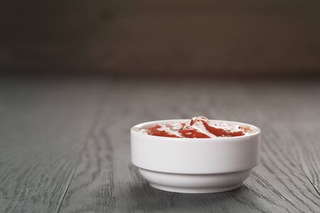 white bowl with tomato sauce on wood table, shallow focus