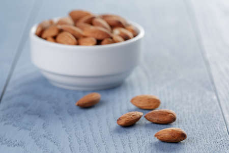 roasted almonds in white bowl on blue wooden tableの写真素材